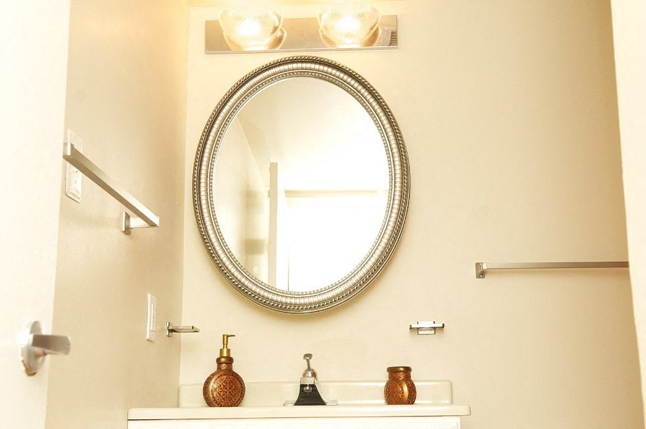 A bathroom with a round mirror and a light above it.