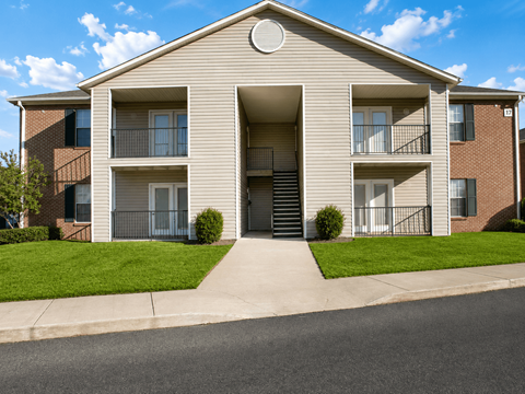 A two-story apartment building with a front lawn and a driveway.