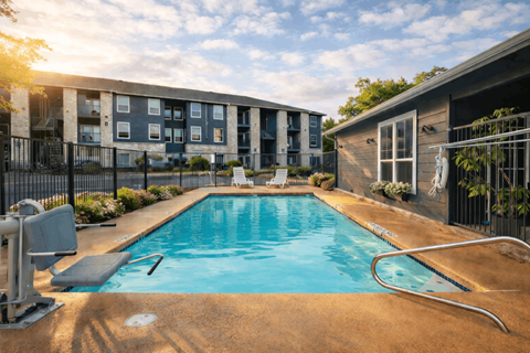 A swimming pool in front of a building with a sunny day.