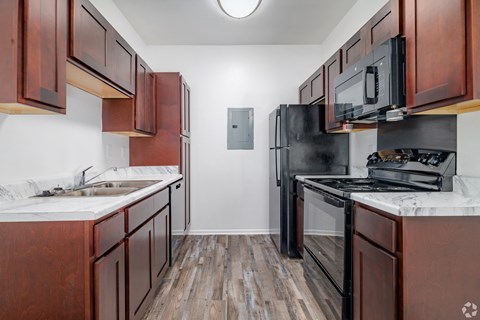 A kitchen with wooden cabinets and a black refrigerator.