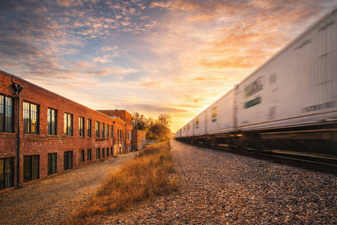 A train is passing by a row of buildings.