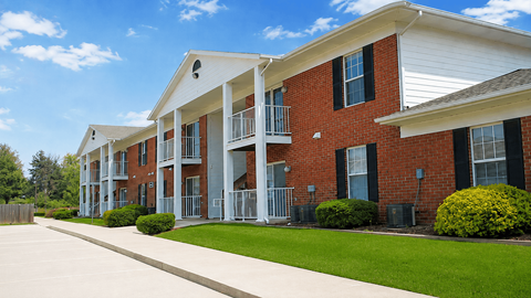A row of red brick apartment buildings with white trim and black shutters.