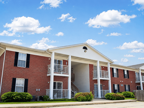 A red brick apartment building with a white roof and a balcony.