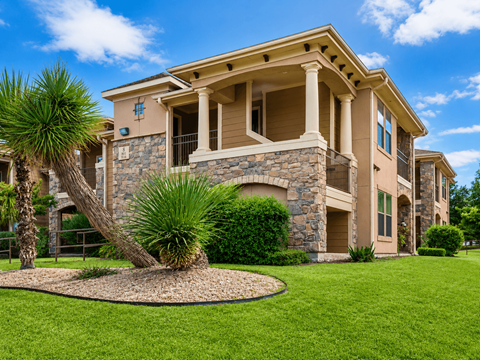 A large house with a stone and wood exterior and a landscaped front yard.