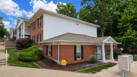 A white house with a red brick front and a driveway.