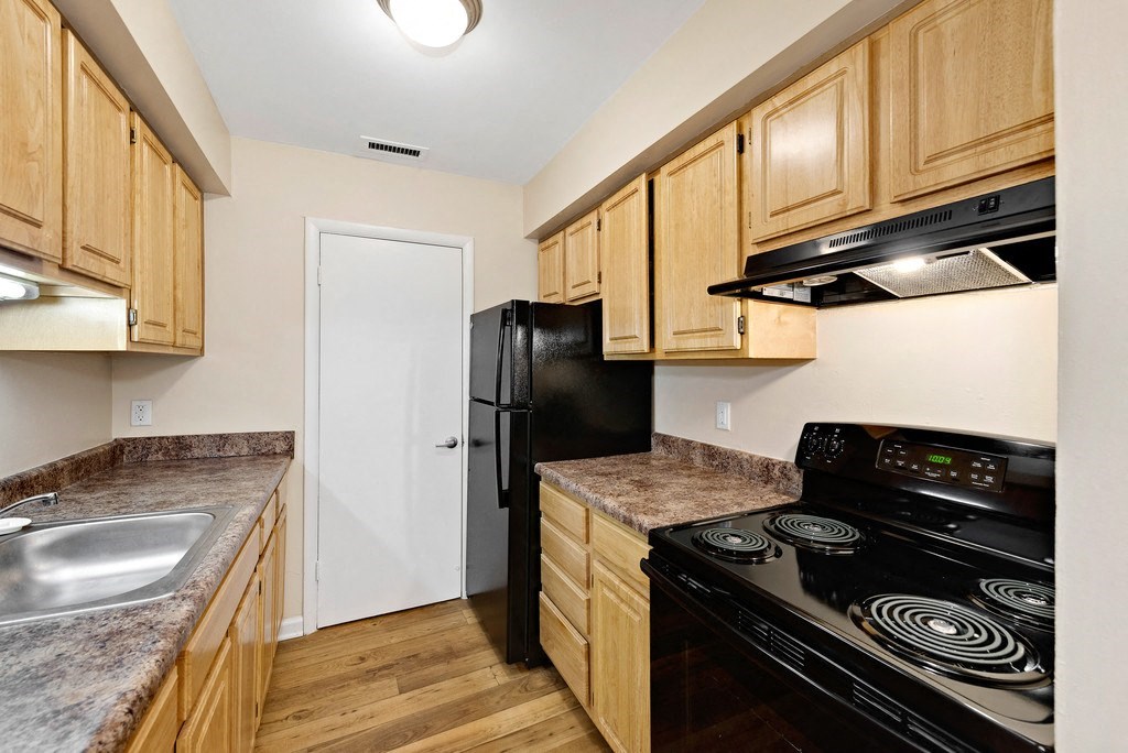 A kitchen with wooden cabinets and a black stove top oven.
