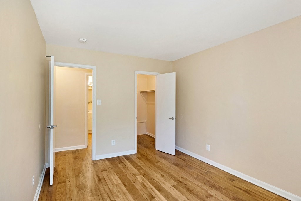 A room with two open doors and wooden floors.