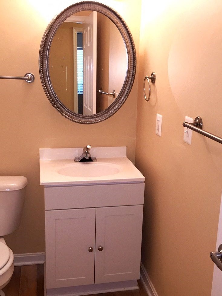 A bathroom with a toilet, sink and mirror.