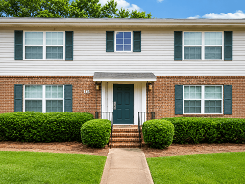 A house with a green door and two windows with green shutters.