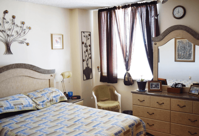 A bedroom with a bed, chair, and a clock on the wall.