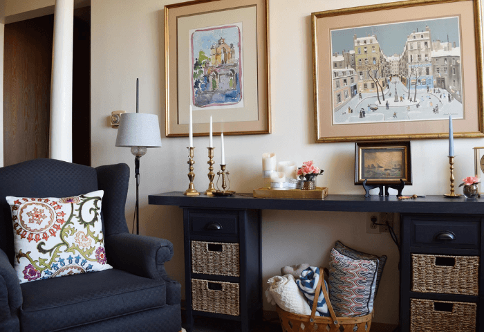 A living room with a black couch and two framed pictures on the wall.