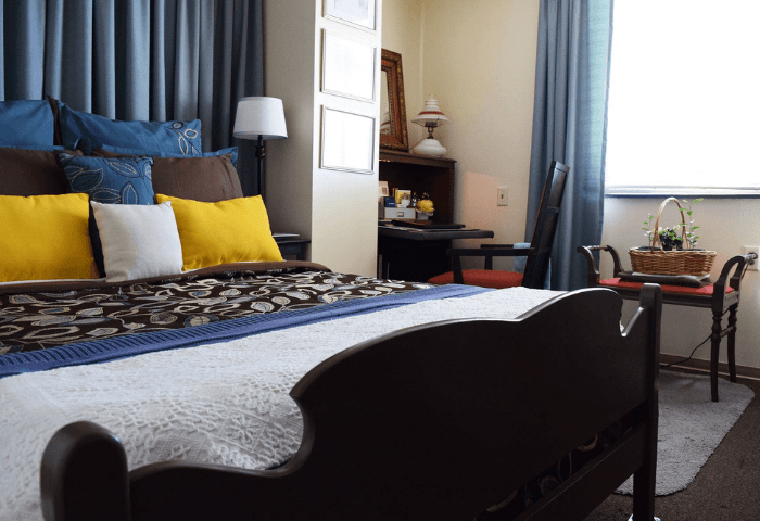 A bedroom with a large bed and a nightstand with a lamp.