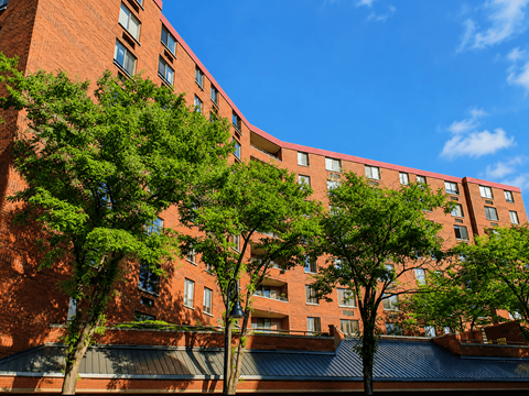 A red brick building with trees in front.