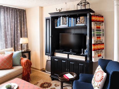 A living room with a black entertainment center and a blue chair.