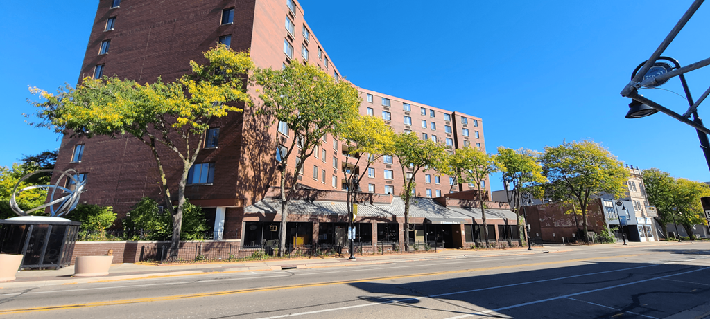 a city street in front of a tall brick building with trees