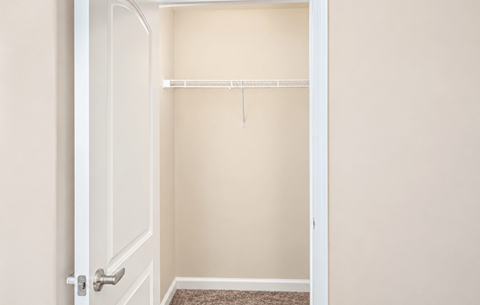 A white door is open to a room with a shelf and a rug on the floor.