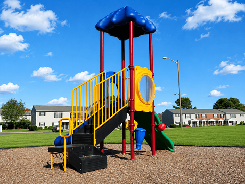 A playground with a blue and yellow slide and a red and yellow staircase.
