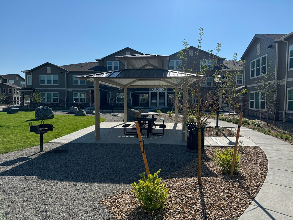a park with a pavilion and picnic table in front of an apartment building