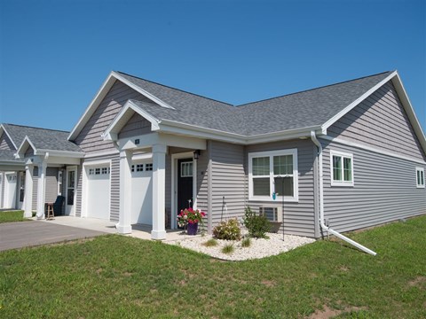 A grey house with a white garage door and windows.