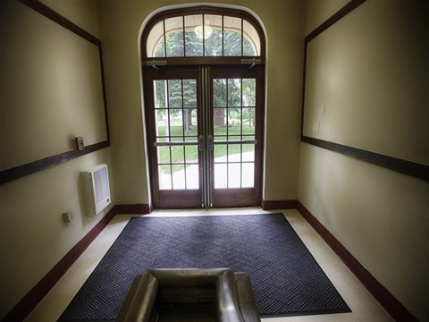 A hallway with a large arched doorway leading to a grassy area.