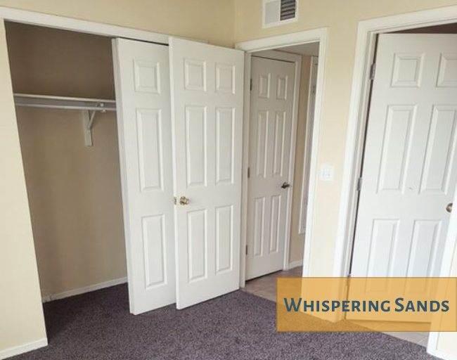 A room with three white doors and a sign that says Whispering Sands.