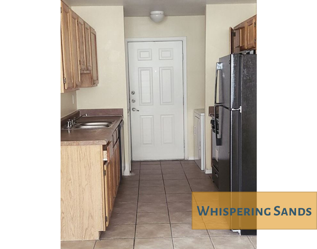 A kitchen with wooden cabinets and a black fridge.