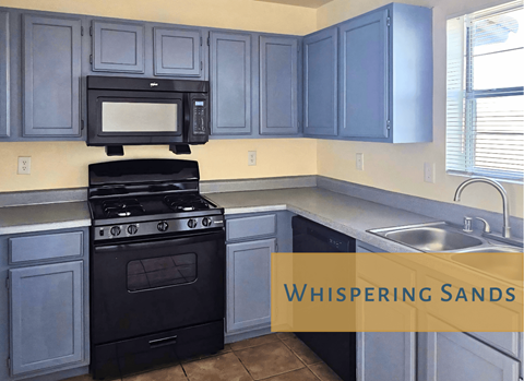 A kitchen with a black stove and cabinets with a window.
