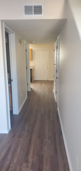 A long hallway with wood floors and white walls.