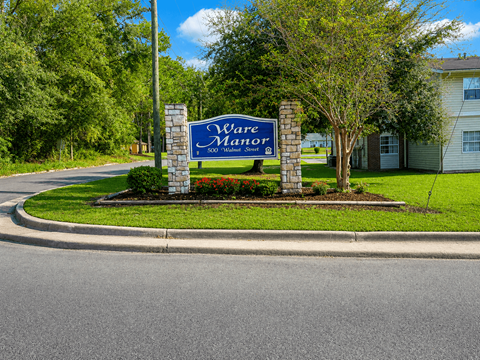A sign that says "Ware Motor" stands in front of a house.