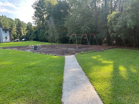 A playground with a swing set and a white line in the middle of a grassy area.