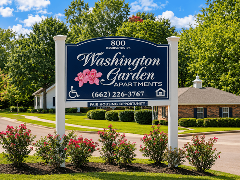 A sign for Washington Garden Apartments stands in front of a building.