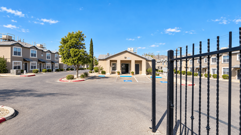 A parking lot in front of a building with a black fence on the right side.