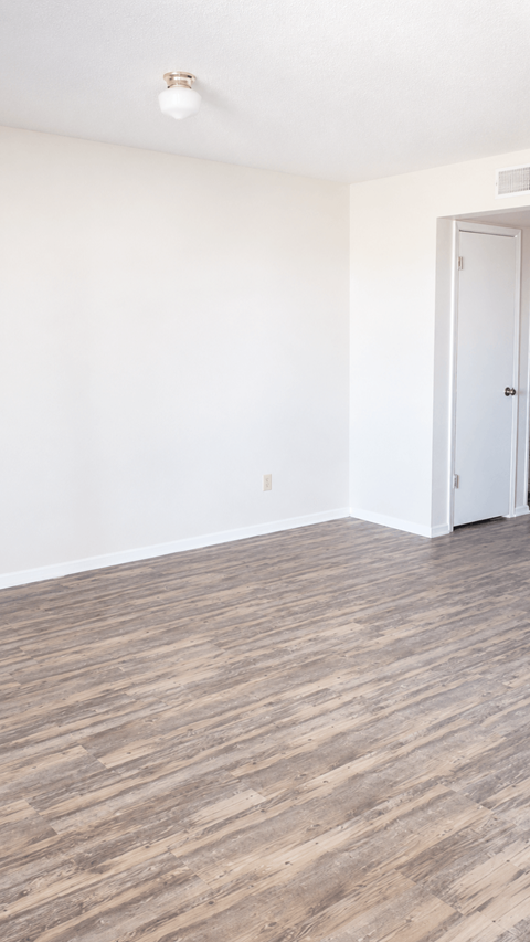 A room with a white door and a light brown floor.