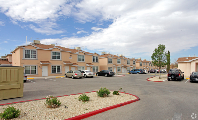 A parking lot in front of a building with cars parked.