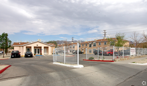 A parking lot with a building and cars parked in front.