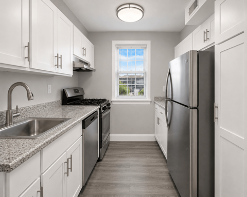 A kitchen with white cabinets and a stainless steel refrigerator.