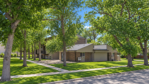 A house surrounded by green trees on a sunny day.