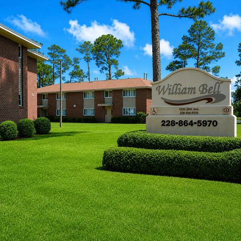 A sign for William Bell stands in front of a building and trees.