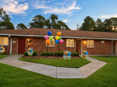 A house with a driveway and a sign that says "Welcome to Sunshine Elementary School".
