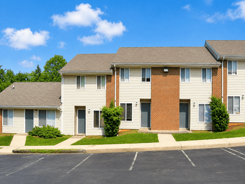 A row of townhouses with a parking lot in front.