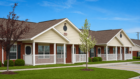 A small house with a brown roof and a white fence.
