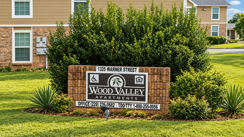 A sign for Wood Valley Apartments is in front of a building.