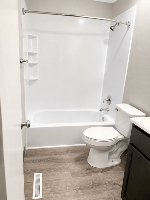 A white toilet sits next to a bathtub in a bathroom.