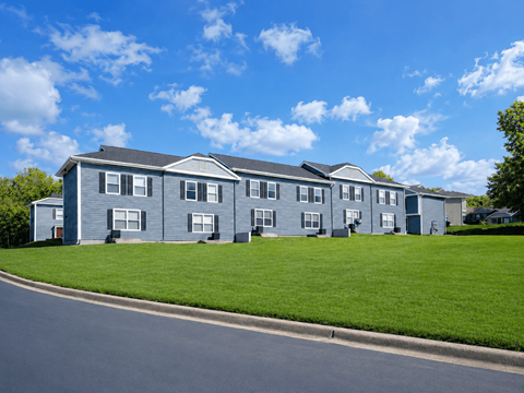A row of houses with a blue sky and clouds in the background.