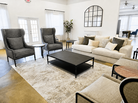 A living room with a grey sofa, two grey armchairs, a black coffee table, and a rug.