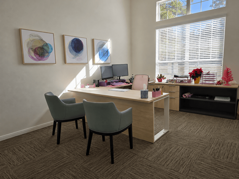 A room with a desk, chairs, and artwork on the wall.