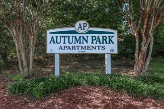 the sign for autumn park apartments in front of trees