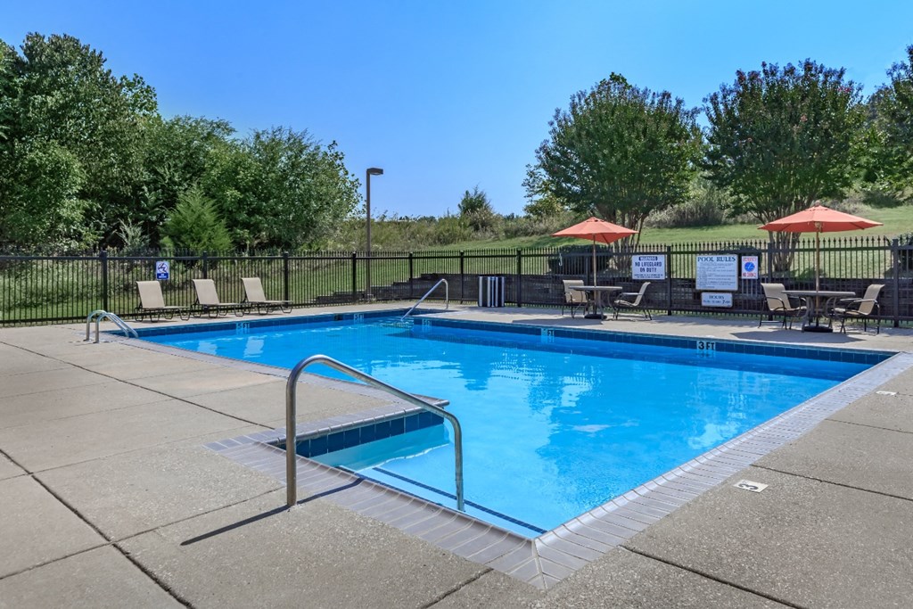 a swimming pool with chairs and umbrellas and a fence around it