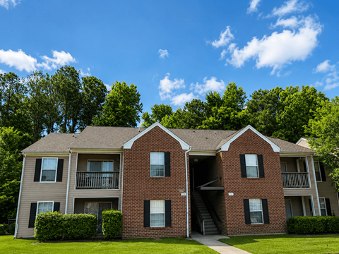 A two-story brick apartment building with a balcony on the second floor.