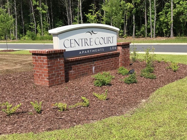 a sign for the centre court apartments on the side of a brick wall
